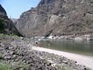 A person walking on a beach toward a kayak above Snow Hole rapid