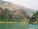 A cataraft gliding toward a layered rock formation