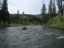 A raft floating through a long bend in the John Day River with grassy hillsides on both banks
