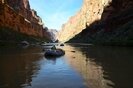 Raft floating down a glassy stretch of the Colorado River in Grand Canyon