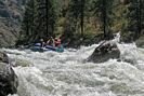 Raft entering rapid with large rock in foreground