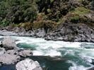 Looking across the Little Green Wall rapid full of whitewater, running against a cliff on the far side of the river