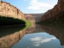 Glassy water disappearing in the distance through a canyon of vertical walls, with the walls and sky reflecting in the waters surface