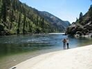Two women standing on a white beach looking down the emerald green Salmon River