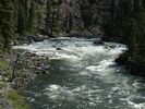 Looking upstream at a rafting party tied off on shore, with a major rapid dominating the picture