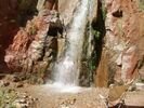 Man standing under waterfall reaching out with thumbs up on Grand Canyon rafting trip